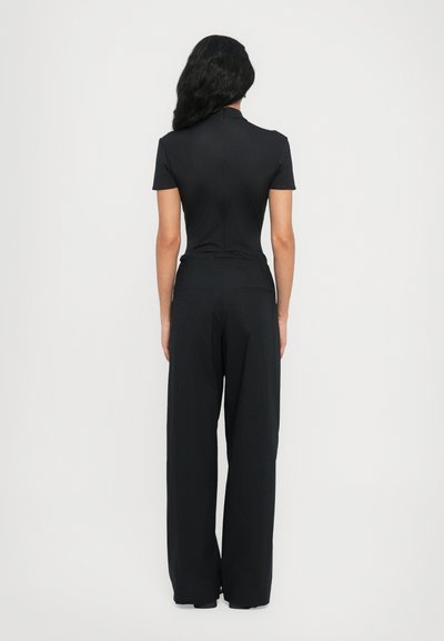 Black jumpsuit featuring a high neckline, short sleeves, and wide-leg pants. Made from smooth fabric with a fitted waist and back seam detail.