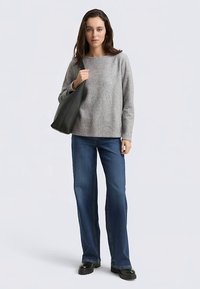 Hall hallast kampsun, lai kaelus, pikad varrukad; kombineeritud siniste lehvikpükstega ja musta nahast õlakotiga. Sile tekstuur, vaba lõikega.