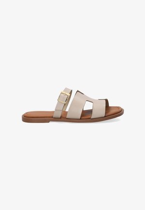 Sandales en cuir beige à enfiler avec un design ouvert à l'avant, comportant deux larges brides et une boucle décorative dorée sur une des brides. Semelle plate marron.