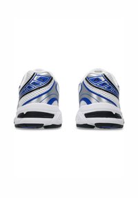 Bílé sportovní boty s vrchní částí z síťoviny, modrými a stříbrnými akcenty a černou gumovou podrážkou. Design obsahuje strukturovaný povrch.