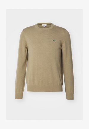 Maglione lavorato a maglia beige con scollo tondo, polsini e orlo a costine, con un piccolo logo di un coccodrillo verde sul lato sinistro del petto.
