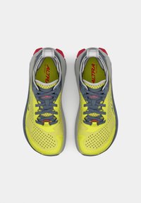 Des chaussures de course jaunes vives avec une tige en mesh respirant, des accents gris, un col rembourré et une semelle texturée avec des détails rouges.