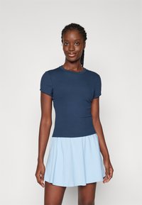 Top aderente blu navy con maniche corte, abbinato a una gonna svasata azzurro chiaro. Tessuto liscio, senza pattern o accenti visibili.