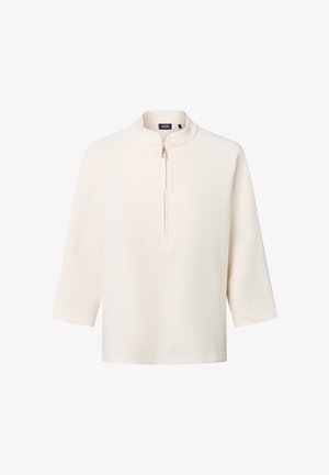 Pull-over zippé beige clair avec des manches trois-quarts, fabriqué à partir d'un tissu doux ; présente un design minimaliste et une texture lisse.