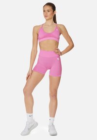 Roze sportbra en bijpassende high-waisted shorts van rekbare stof. Heeft een subtiele glans, logo-detail en een aansluitend ontwerp.