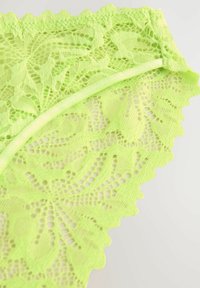 Neon-grüne Spitzenunterwäsche mit floralem Muster, gewellten Kanten und einer weichen Textur. Verfügt über dehnbares Material und einen glatten Bund.