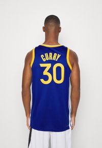 Maglia da basket blu royal con accenti gialli, "CURRY" sopra il numero "30" sul retro, realizzata in un tessuto leggero e traspirante.