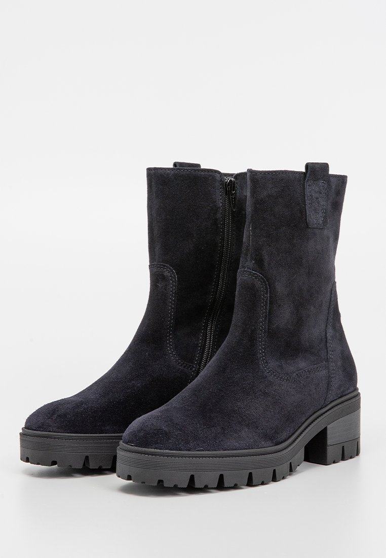 Un paio di stivali neri in suede, al polpaccio, con cerniere laterali, linguette per l'estrazione, suole in gomma spessa e tacco basso, su sfondo bianco.