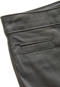 Grijze denimstof met zichtbare stikdetails. Heeft een achterzak, rechthoekige vorm en een gladde textuur.