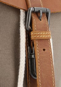Hnědý kožený pás s kovovou sponou, připevněný k béžovému plátěnému tělu; obsahuje béžový propletený materiál a detaily šití.