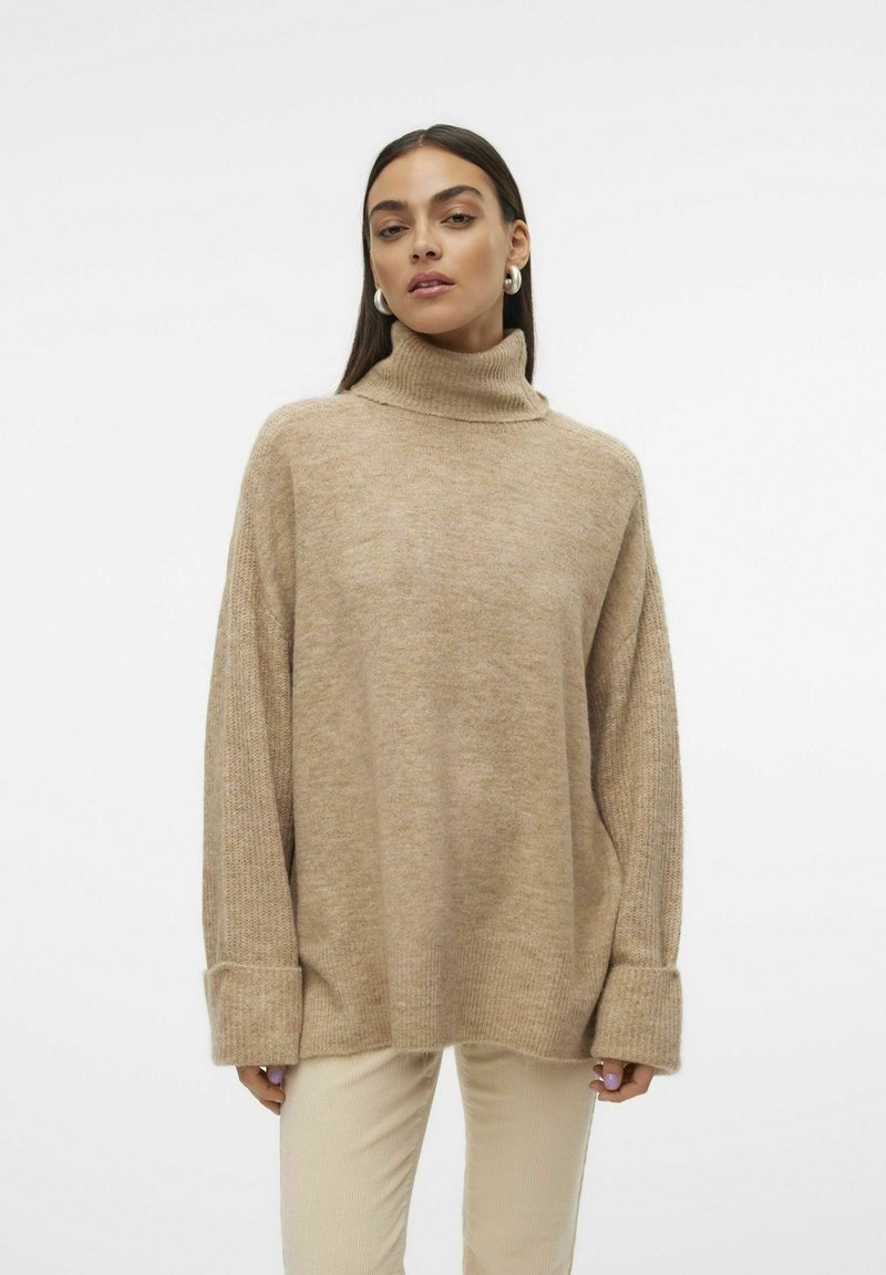Beige Rollkragenpullover aus weichem, strukturiertem Strick mit oversized Fit und langen, weit geschnittenen Ärmeln. Gerippter Saum und Bündchen. Heller Hintergrund.