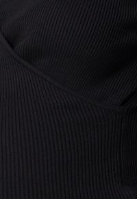 Black ribbed textile featuring a textured, patterned surface. The fabric shows vertical ribs and a fitted design, emphasizing a sleek appearance.