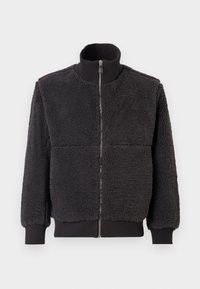 Jachetă din fleece neagră cu guler înalt, fermoar frontal și manșete ribbate. Prezintă o suprafață texturată, pufoasă și o croială lejeră.