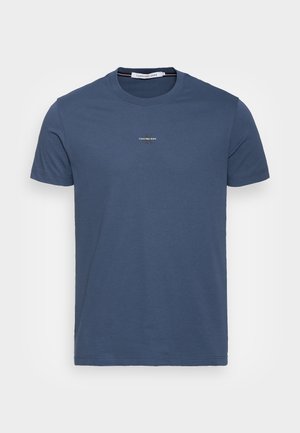 T-shirt en coton bleu marine avec un col ras du cou, des manches courtes et un petit logo blanc sur la poitrine. Texture lisse et design à coupe classique.