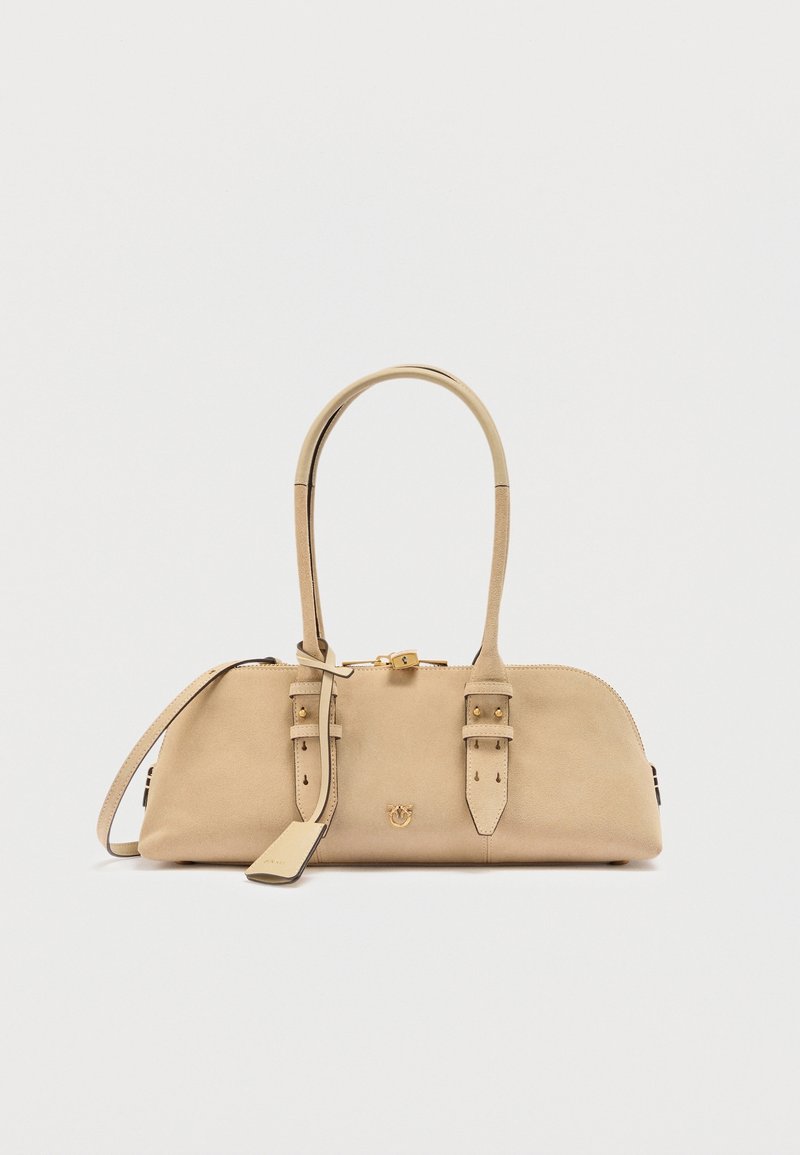 Sac à main en cuir beige avec deux poignées supérieures, détails de sangle à boucle, un petit logo doré et une fermeture éclair sur fond blanc.