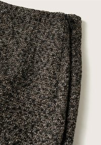 Tissu tissé gris foncé avec des éclats intriqués de noir et de marron. Présente une fermeture éclair lisse sur le bord supérieur. Fini texturé et structuré.