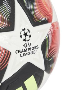 Balón de fútbol en blanco y negro con vibrantes patrones en rojo y verde en espiral. Presenta el logo de la UEFA Champions League, diseño de estrellas y superficie texturizada.