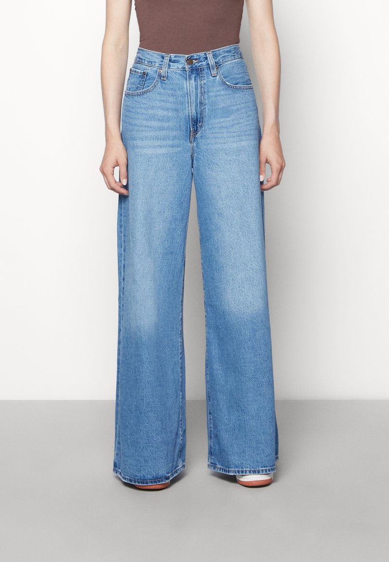 Vida jeans i blå denim med hög midja, ljus tvätt och subtila slitningar. Har en traditionell femfickorsdesign och metallknappstängning.