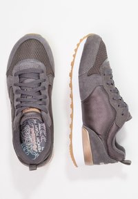 Grå sneakers med nät- och mockamaterial, med en texturerad design, vit mellanläggen och gummisula. Accentdetaljer i metalliska nyanser.