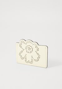 Portafoglio in pelle crema con parte superiore scallop e design perforato floreale. Presenta bordi neri e una texture liscia, di forma rettangolare compatta.