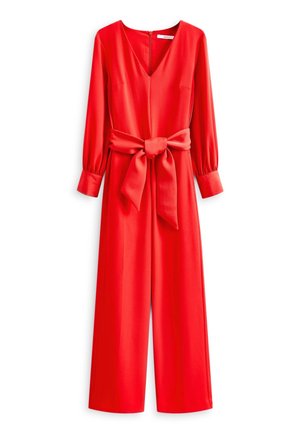 Combinaison rouge à manches longues avec col en V, jambes larges, poignets boutonnés et une grande ceinture nouée à la taille.
