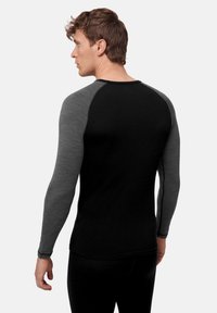 Koszula z długim rękawem o czarnym korpusie i szarych rękawach raglanowych, wykonana z miękkiego materiału. Posiada dopasowany krój zapewniający komfort i swobodę ruchów.