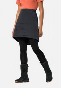 Gewatteerde zwarte rok met een diagonale zoom en verticale naden. Draagt over zwarte legging en in combinatie met hoge zwarte suède laarzen.