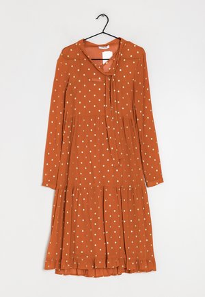 Rostfarbendes Langarmkleid mit weißen und goldenen Punkten, einem gebundenen Ausschnitt, einem gestuften Rock und Rüschendetails am Saum.