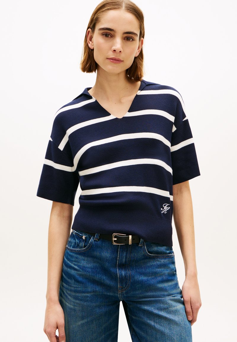 Κοντομάνικη μπλούζα με ριγέ σκούρο μπλε και λευκό, με V-λαιμόκοψη, κατασκευασμένη από μαλακό πλεκτό ύφασμα, με κεντημένο λογότυπο στο στρίφωμα.