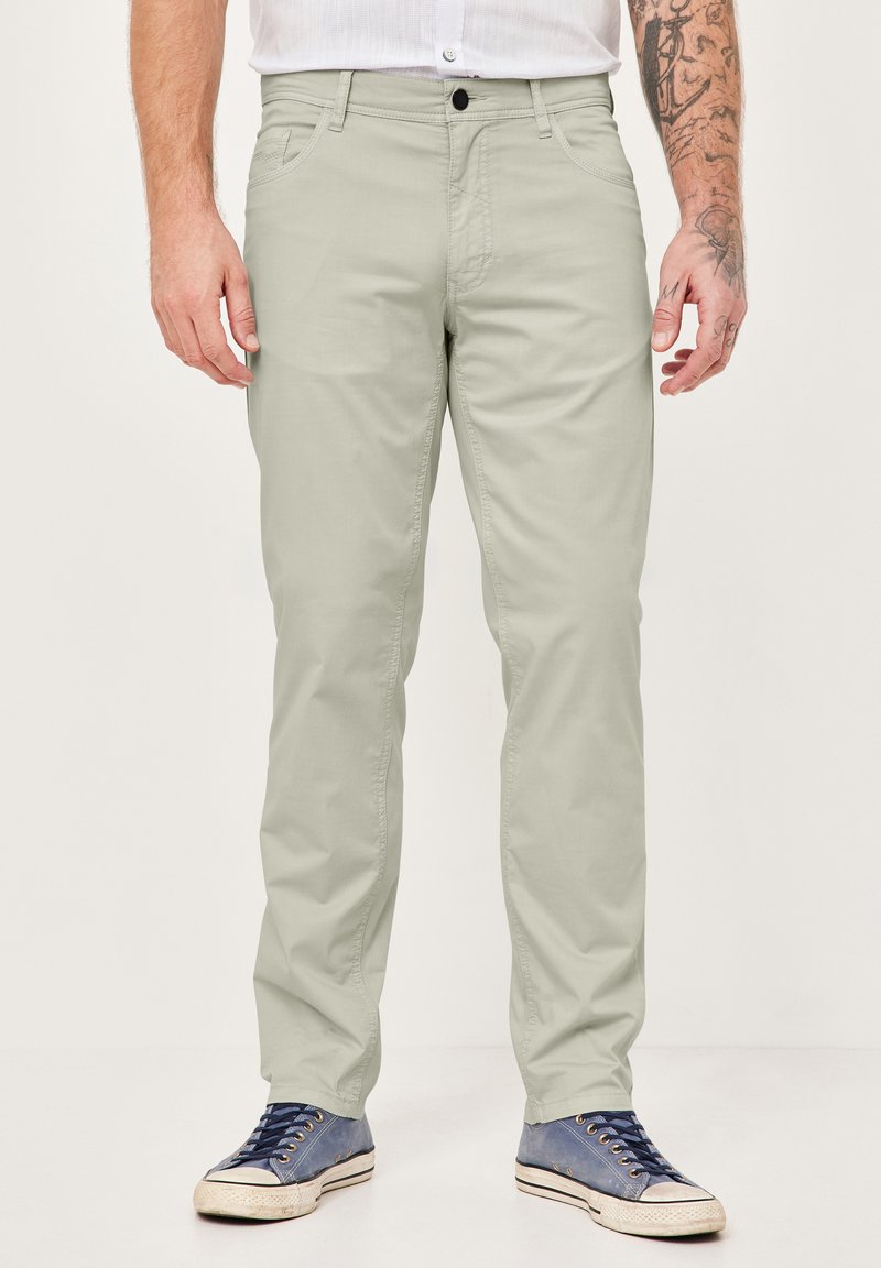 Hellegraue Baumwollchinos mit gerader Beinform, Fronttaschen, einem Knopfverschluss, kombiniert mit blauen und grauen Sneakers.