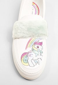 Białe wsuwane buty na płótnie z miękkim paskiem z mięciutkiego futerka w mięcie. Na cholewce znajduje się kolorowa grafika jednorożca i tęczowy wzór.