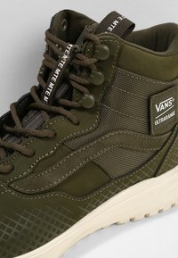 Zapatillas altas Ultramarine de Vans en verde, con tejido texturizado y cuero suave, que presentan cordones marrones, parche del logo y suela de goma con diseño en cuadrícula.