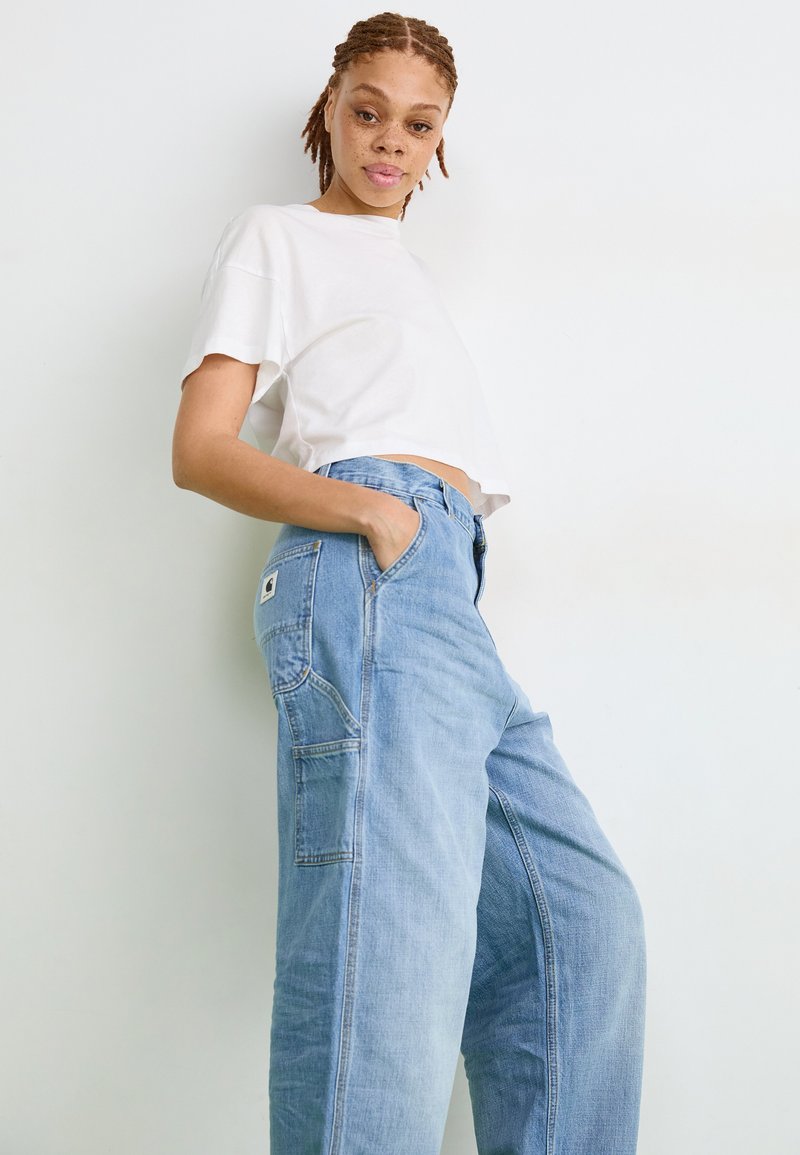 Lichtblauwe denim cargobroek met een relaxte pasvorm, voorzien van zijzakken, en een witte cropped t-shirt. Soepele textuur, casual ontwerp.