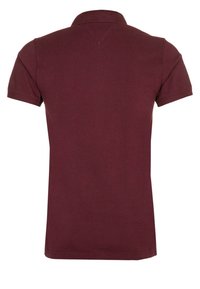 Maroon polo-paita, jossa on kauluksellinen kaula ja lyhyet hihat. Kangas näyttää sileältä, ja se on klassisen mallinen, jossa on kevyt ribbaus kauluksessa ja hihojen päässä.