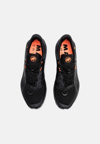 Czarne buty sportowe z siateczkową cholewką, pomarańczowymi akcentami i dynamicznym systemem sznurowania. Posiadają teksturowane wzory oraz wyściełane wnętrze.