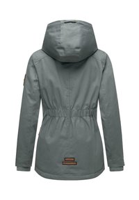 Szürke dzseki állítható kapucnival, elasztikus derékpánttal és bordás mandzsettákkal. A hátán és az ujjakon logó foltok találhatók. Sima textúrájú.