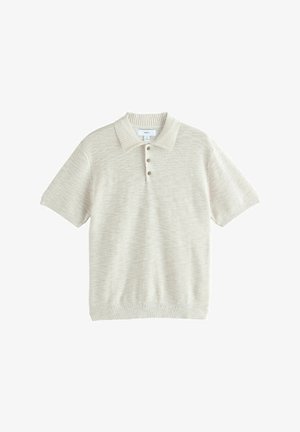 Suéter tipo polo beige de manga corta en punto texturizado. Cuenta con cuello acanalado, tapeta de tres botones y un ajuste relajado.