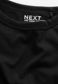 Sort langærmet crew neck t-shirt lavet af blødt bomuld. Har en glat tekstur med syns detaljer og et mærkat, der viser mærkets navn.