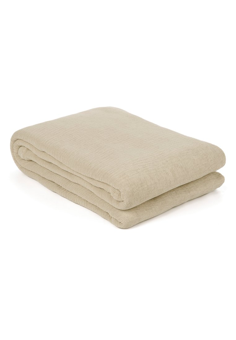Manta de punto beige doblada con un tejido texturizado, colocada sobre un fondo blanco.