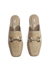 Mules beiges tissés à enfiler avec une surface texturée, un bout carré et des accents en métal doré sur la bride avant.