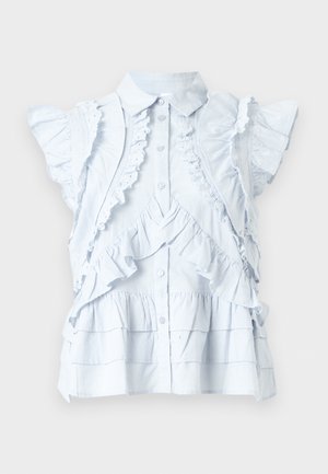 Blouse blanche sans manches avec détails à volants, bordure en dentelle, boutons sur le devant et ourlet à étages, présentée sur fond uni.