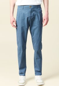 Ljust blå chinos med rak bendesign, tillverkade av andningsbart tyg, med knappstängning och snedställda fickor. Stylade med vita sneakers.