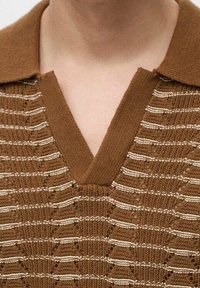 Hnědý pletený polo svetr s véčkovým výstřihem, který má střídající se texturované pruhy a tenké bílé akcenty po celé tkanině.