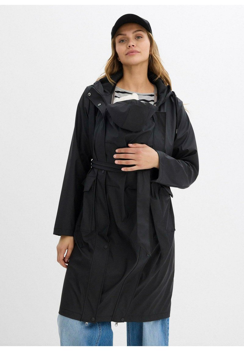 Impermeabile nero con cappuccio, cintura e numerose tasche. Presenta una superficie liscia e un design moderno e funzionale. Adatto per il maltempo.