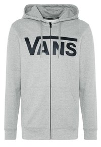 Sudadera con cremallera gris hecha de un tejido suave, con un logotipo frontal en letras negras en negrita. Tiene capucha con cordón y bolsillos laterales.