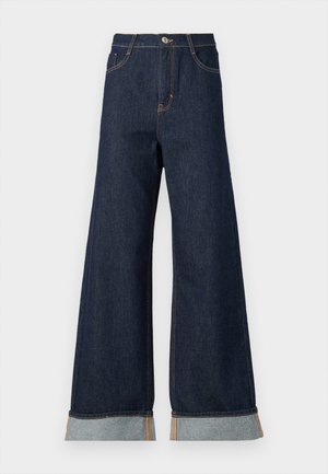 Brede broekspijpen in donkerdenim met oranje stiksel, met een hoge taille, twee voorzakken en omgeslagen manchetten die een lichtblauwe contraststof laten zien.