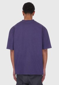 Camiseta de algodón morada con un corte relajado, mangas cortas y cuello redondo. Diseño minimalista, textura suave y sin patrones o acentos visibles.