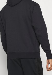 Mörkblå hoodie tillverkad av mjuk bomullsblandning, med kenguruficka, ribbade muddar och nederkant samt en avslappnad passform.