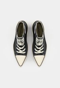 Juoda aukštakulniai sportiniai bateliai su baltais raišteliais ir pirštų dangteliu, su glotnia tekstūra ir kontrastinga trikampio logotipu šone.