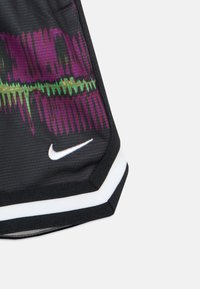Sorte atletikshorts med tekstureret stof. Har et farverigt abstrakt mønster i lilla og grøn, afsluttet med en hvid Nike-logo og kant.